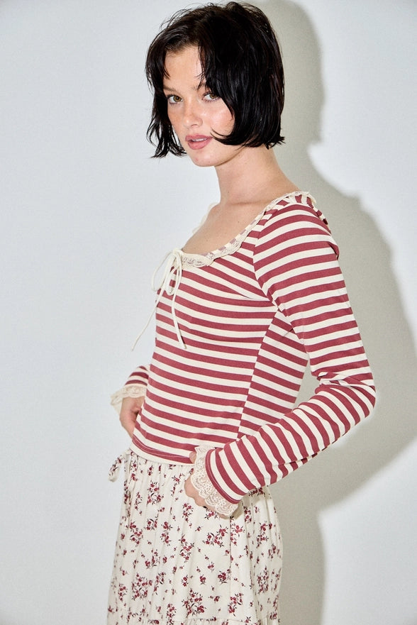 Woman wearing a red and white striped shirt with a floral skirt against a plain background