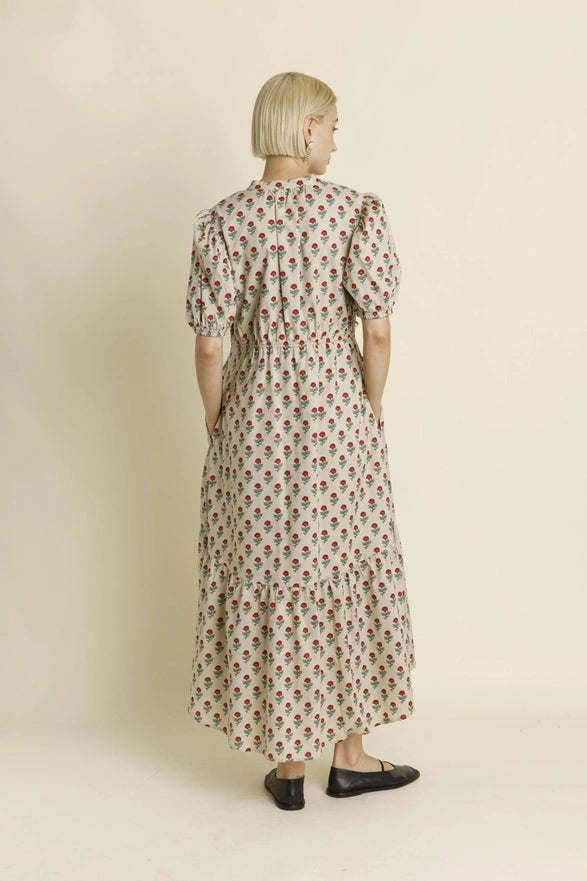 Woman wearing a long floral dress against a beige background