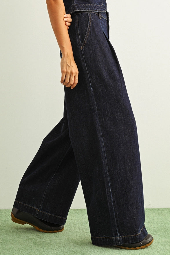 Person wearing dark blue wide-leg jeans on a light green floor.