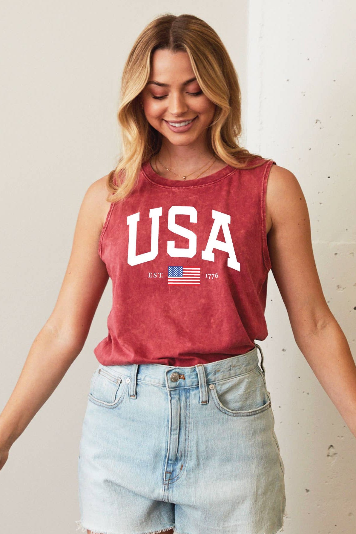 Woman wearing a red 'USA' tank top with an American flag graphic on a plain background