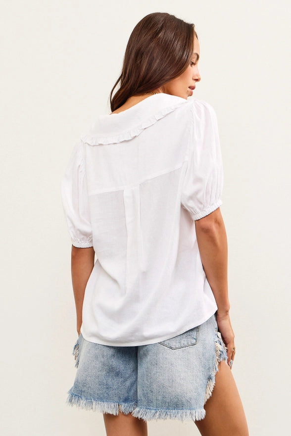 Woman wearing a white blouse and denim shorts on a plain background