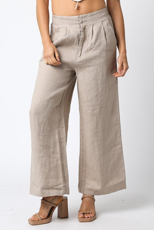 Beige linen pants worn by a person on a white background