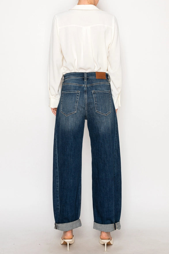 Person wearing blue jeans and a white shirt on a plain background