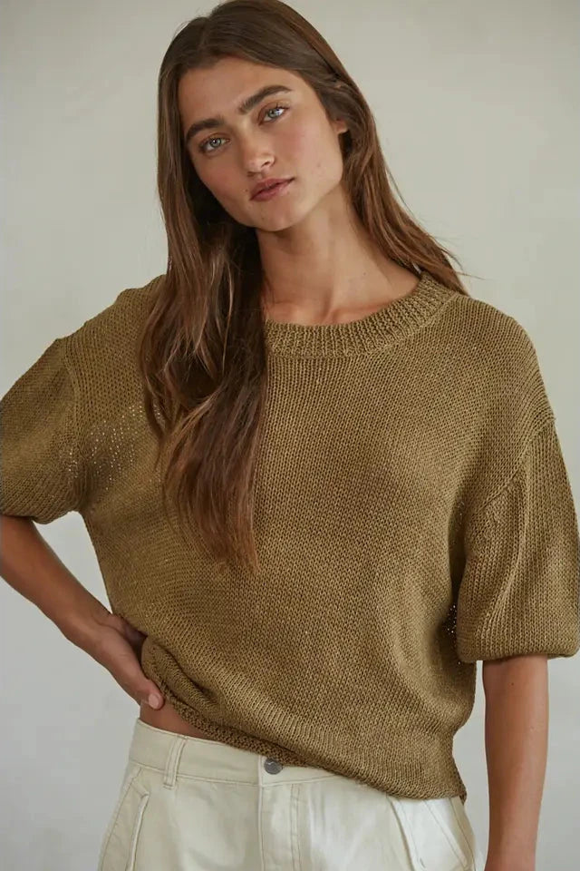 Woman wearing a brown knitted sweater against a plain background