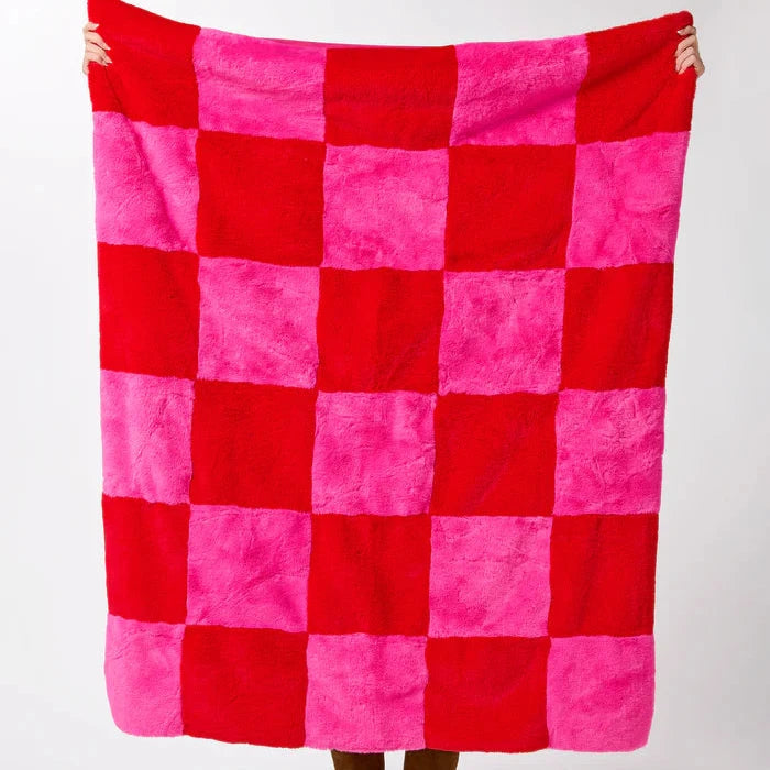 Person holding a red and pink checkered blanket against a white background