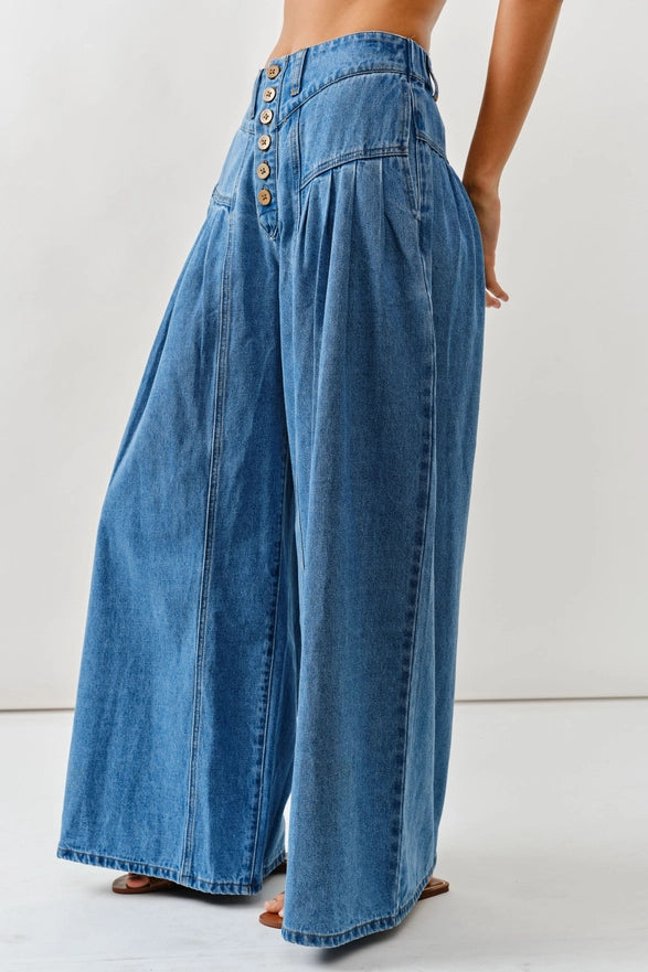 Wide-leg blue jeans worn by a person on a white background