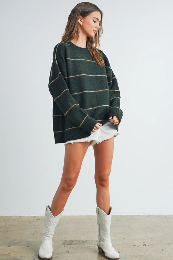 Woman wearing a green striped sweater, white skirt, and white boots on a plain background