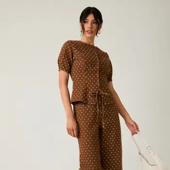 Woman wearing a brown polka dot outfit against a white background