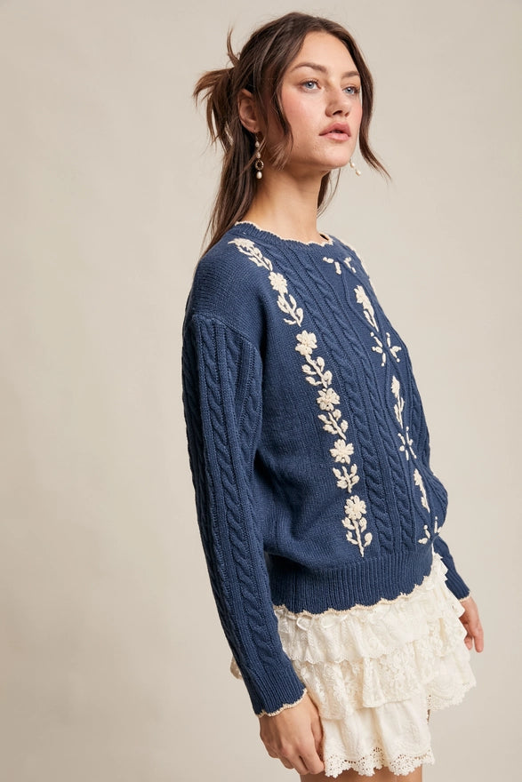 Woman wearing a blue sweater with floral patterns on a beige background