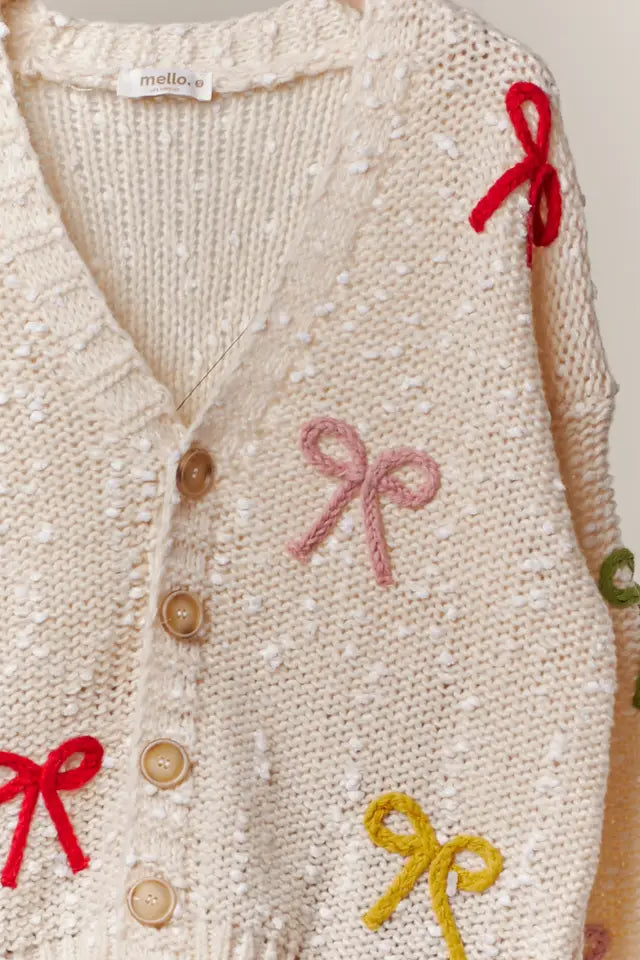 Knitted cardigan with colorful bows and buttons on a plain background