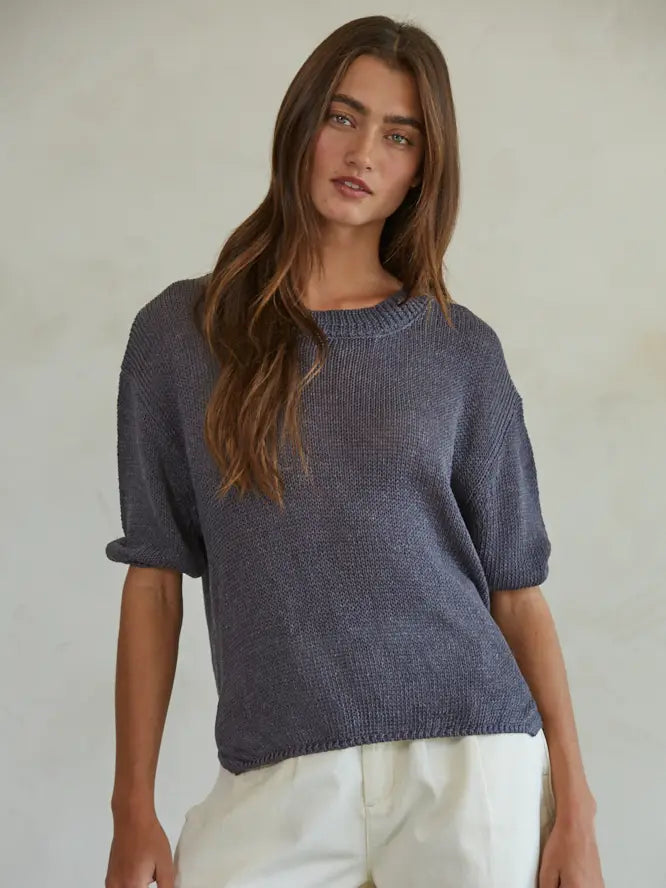 Woman wearing a dark blue knitted sweater against a plain background