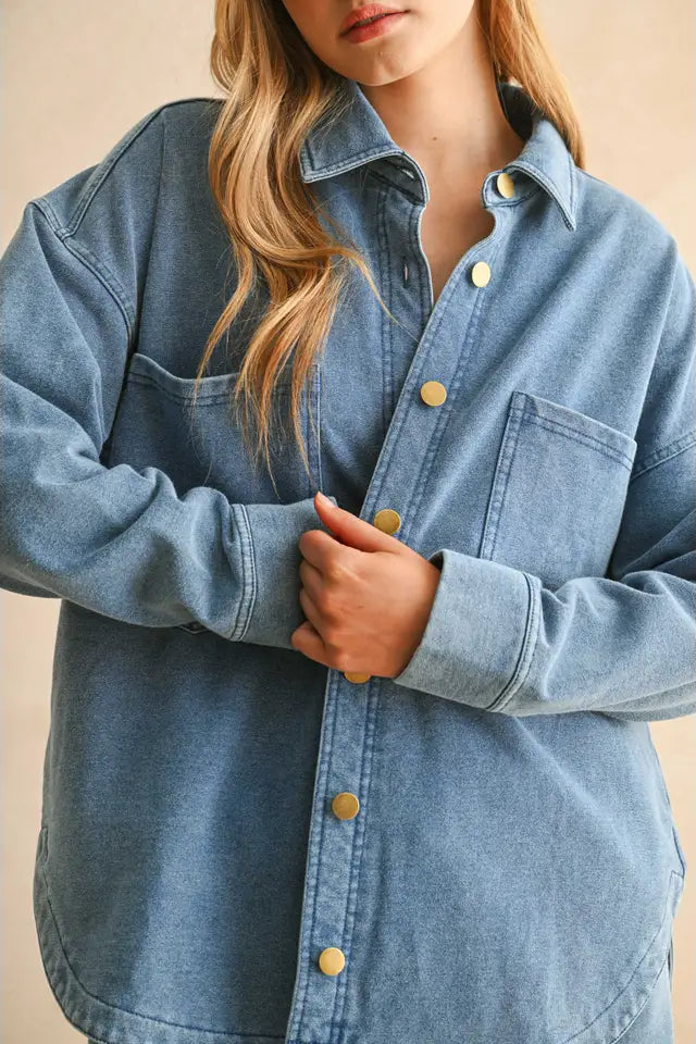 Denim shirt with button details worn by a person on a beige background