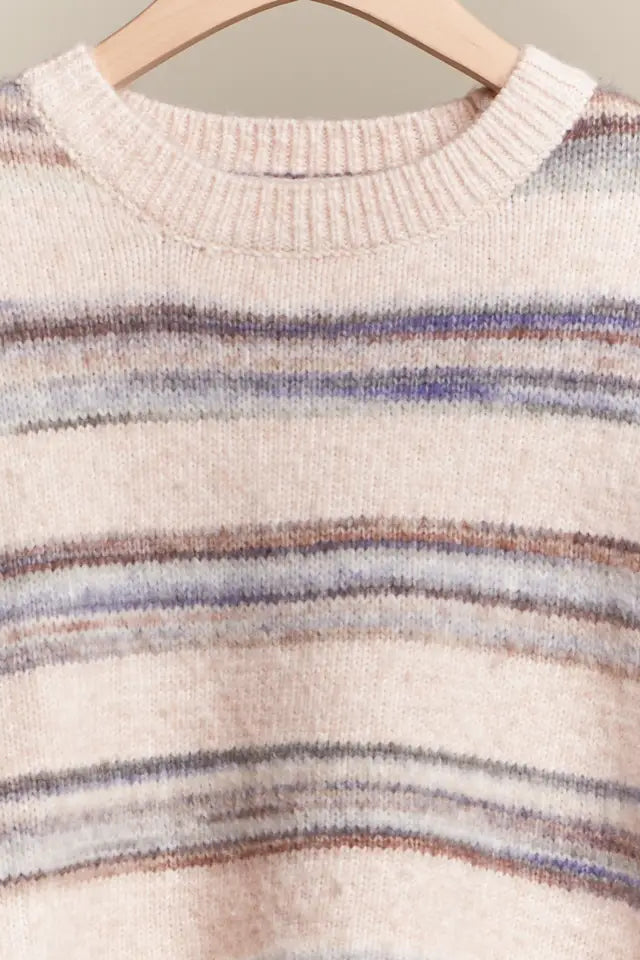 Close-up of a sweater with multicolored stripes on a hanger against a neutral background