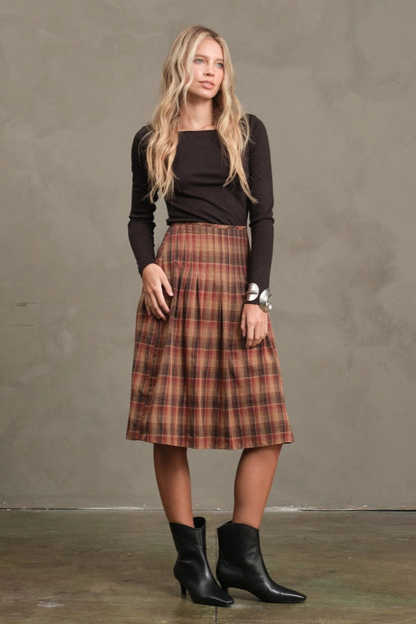 Woman wearing a plaid skirt and black top against a plain background