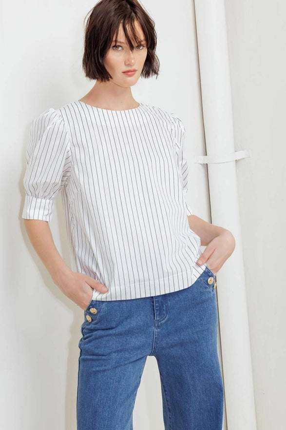 Woman wearing a striped shirt and blue jeans against a white background