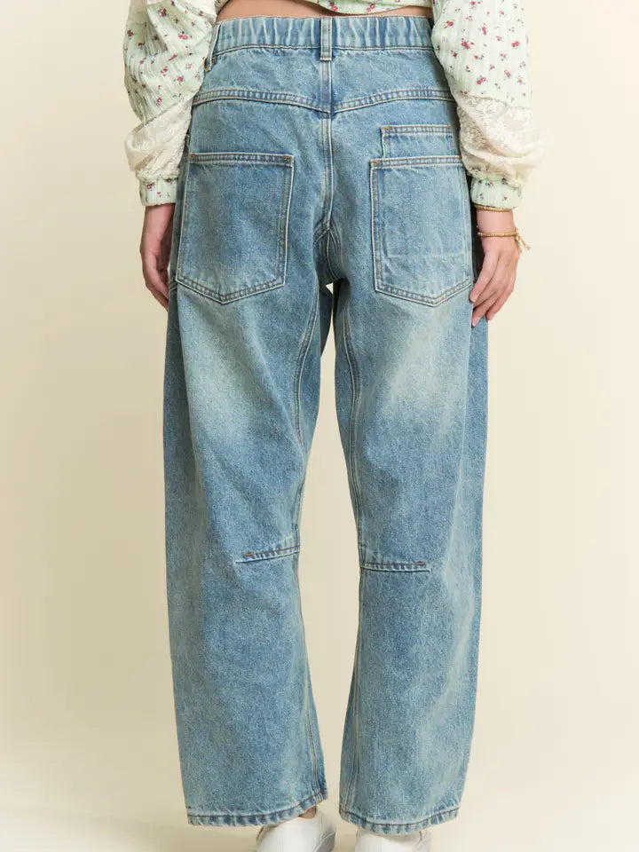 Person wearing light blue jeans on a beige background