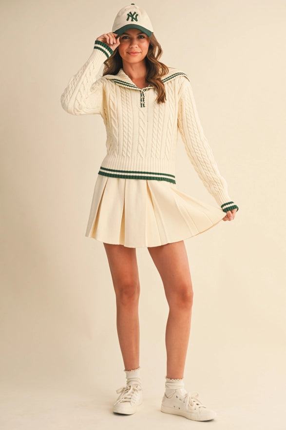 Woman wearing a vintage-style tennis outfit with a cream dress and green accents on a beige background