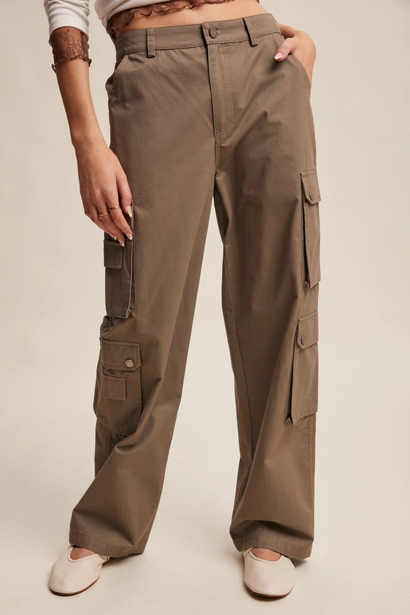 Girl wearing mocha colored cargo pants on plain background.