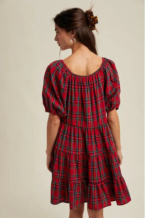 Woman wearing a red plaid dress with puff sleeves on a beige background