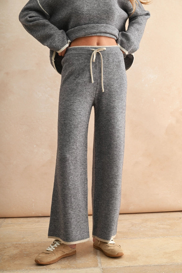 Person wearing gray sweatpants with a beige background