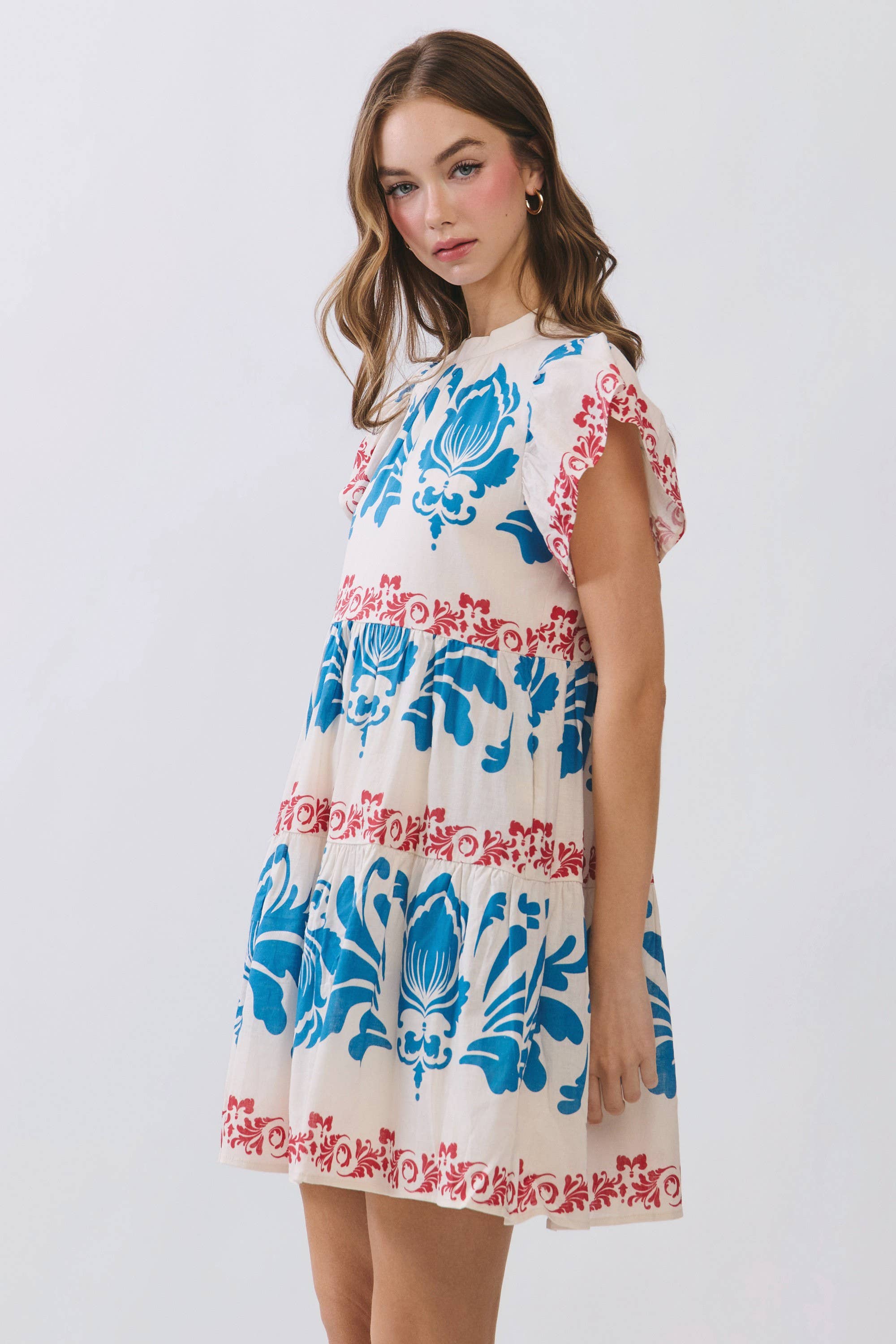 Woman wearing a floral dress with blue and red patterns on a white background