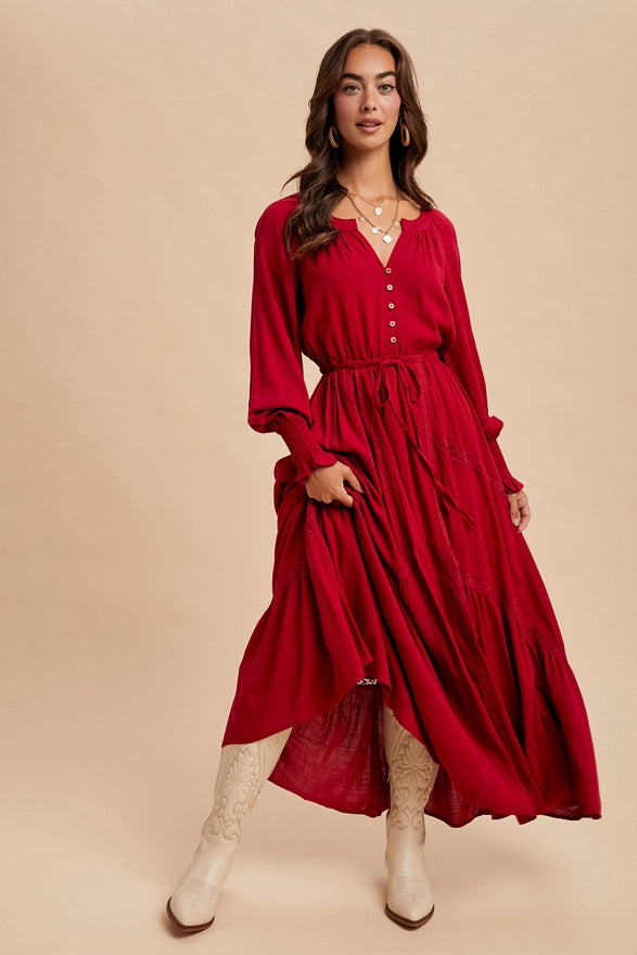 Woman wearing a cherry color maxi dress with long sleeves on plain background