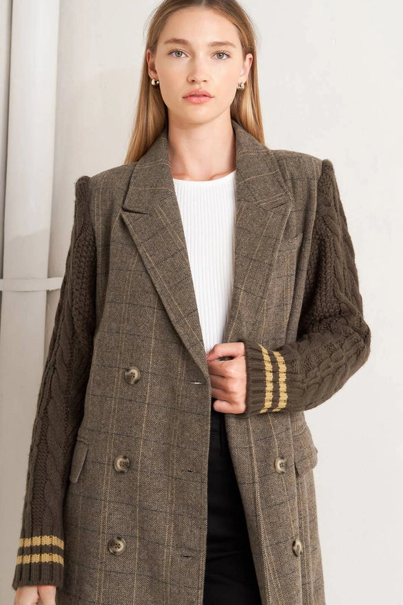 Woman wearing a brown checkered coat with gold trim on a white background