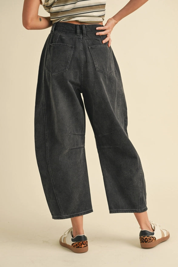 Person wearing black wide-leg pants on a beige background