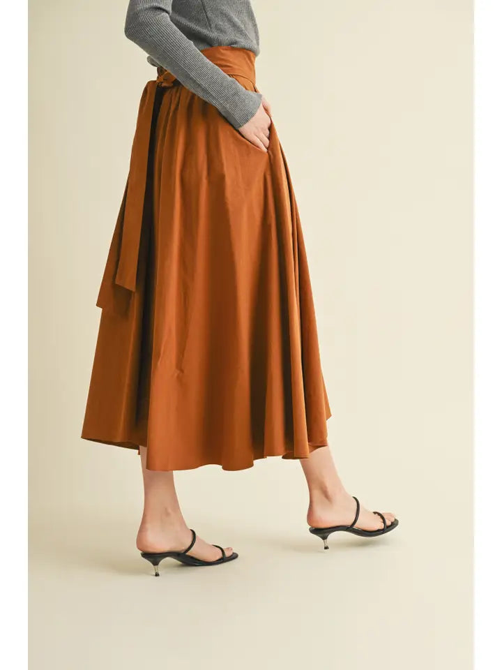 Person wearing a brown tiered skirt on a beige background