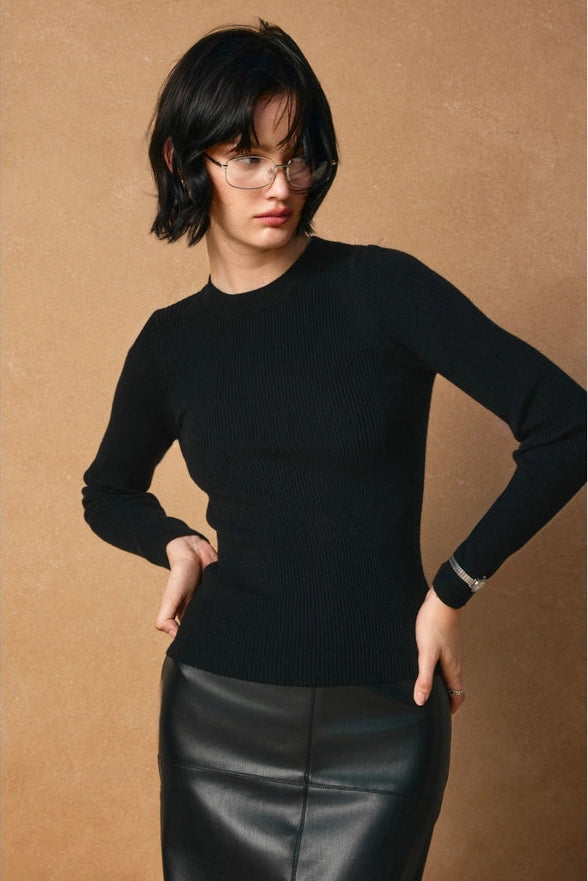 Woman wearing a black sweater and black leather skirt against a brown background