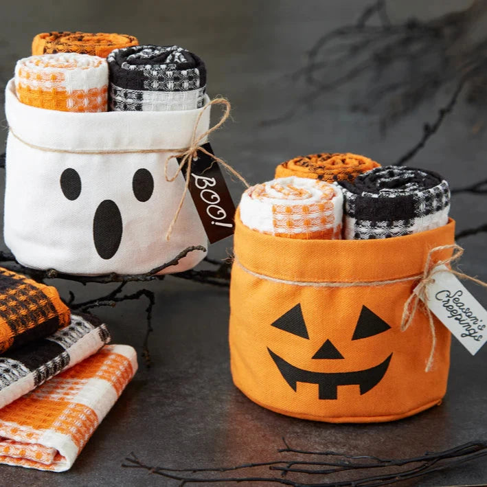 Halloween-themed towel sets in ghost and pumpkin containers on a dark background.