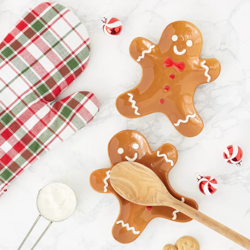 Gingerbread cookies shaped like people with a wooden spoon on a white background.