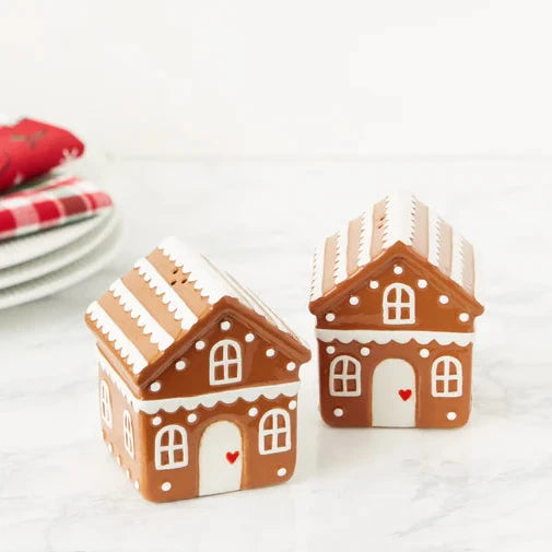 Two gingerbread house-shaped containers on a white surface with red and white checkered napkins in the background.