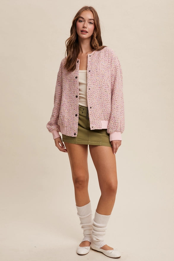 Woman wearing a pink jacket, white top, green skirt, and white socks on a beige background