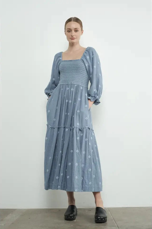 Woman wearing a blue patterned dress against a white background