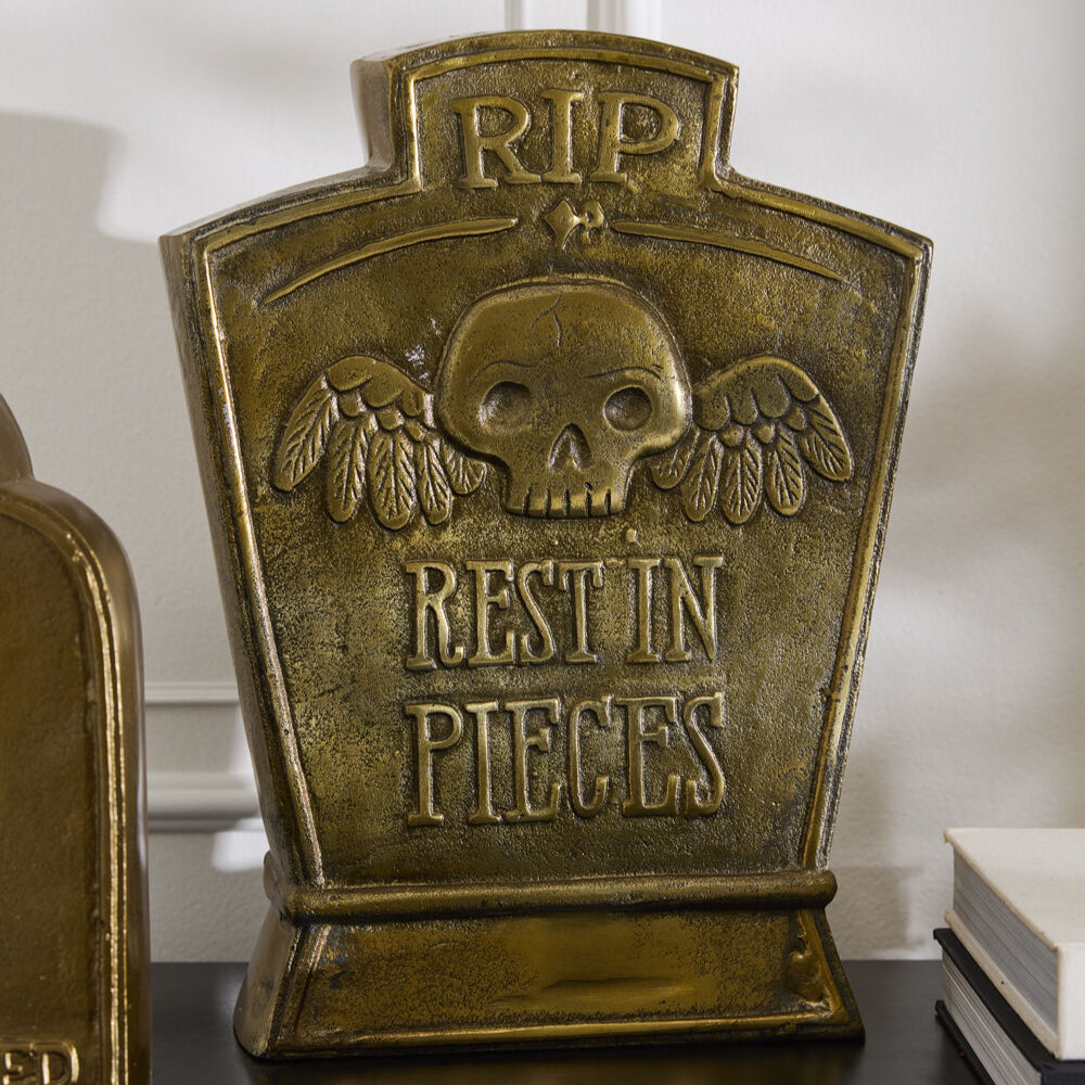 Decorative bookend with skull and wings design on a shelf.