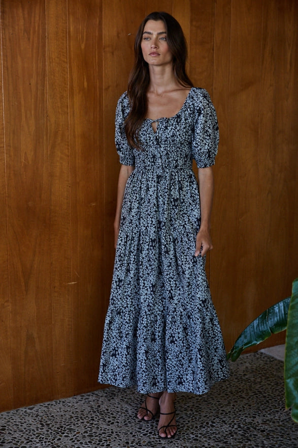 Woman wearing a black and blue maxi dress against a wooden background