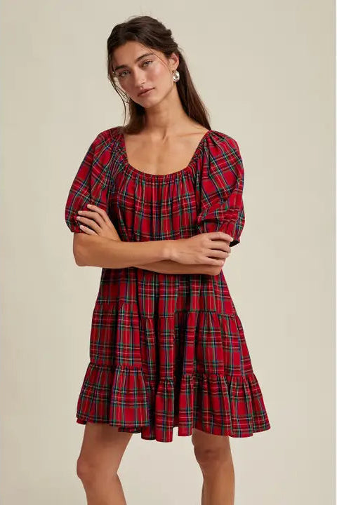 Woman wearing a red plaid dress against a beige background