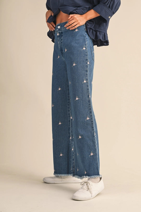 Person wearing blue jeans with star patterns and white sneakers on a beige background