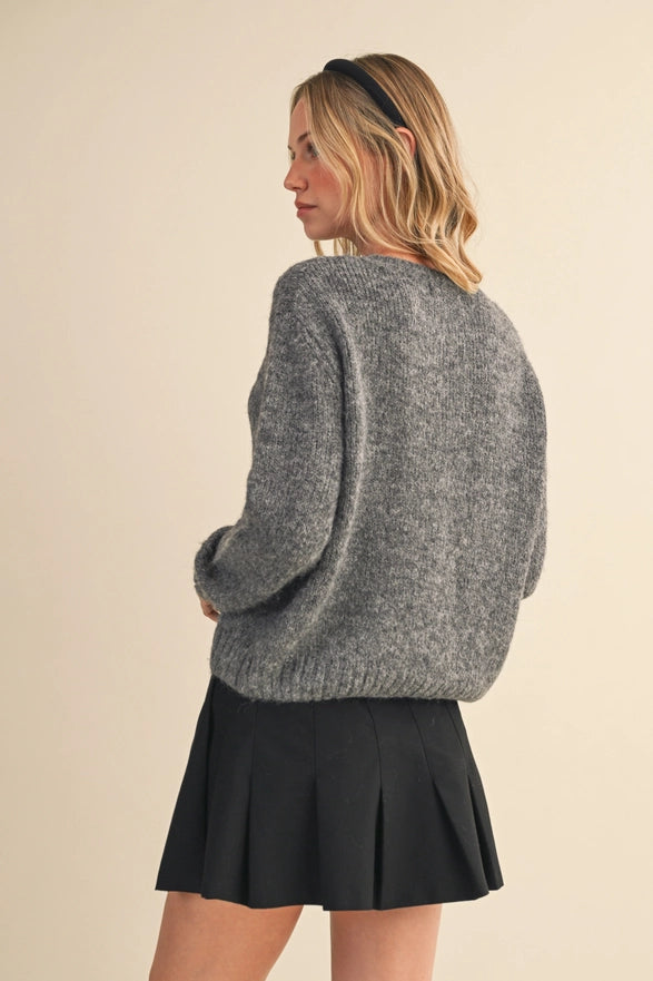Woman wearing a gray sweater and black skirt on a beige background