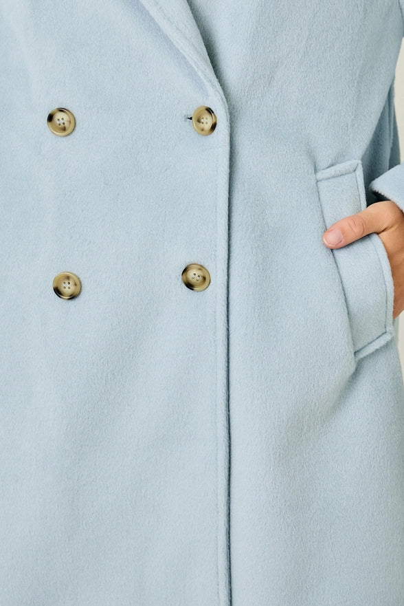 Light blue coat with gold buttons and a hand in the pocket