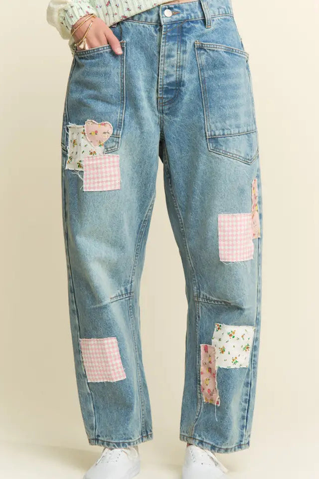 Blue jeans with pink and white patchwork design on a beige background