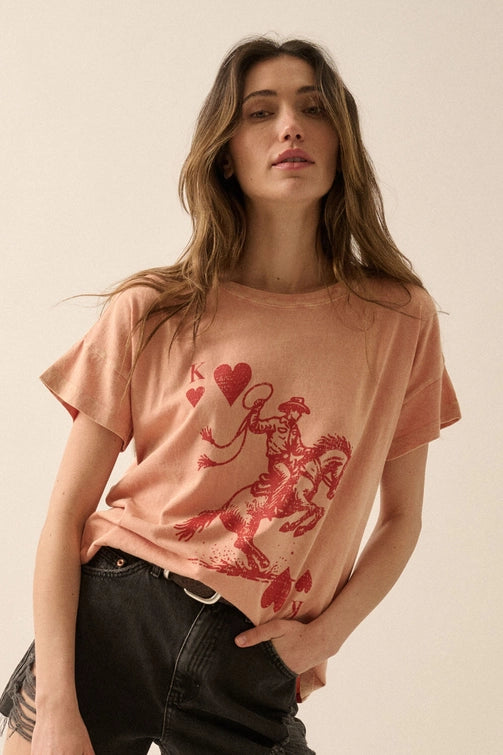 Woman wearing a peach-colored t-shirt with a graphic design on a beige background