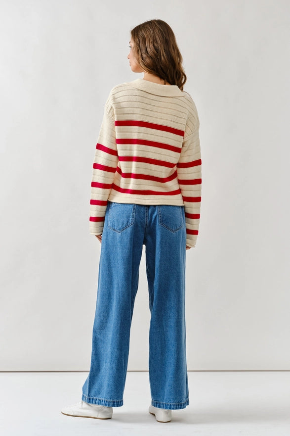 Person wearing a striped sweater and blue jeans against a white background