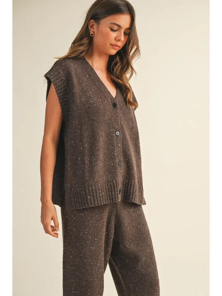 Woman wearing a brown knitted vest and pants on a beige background