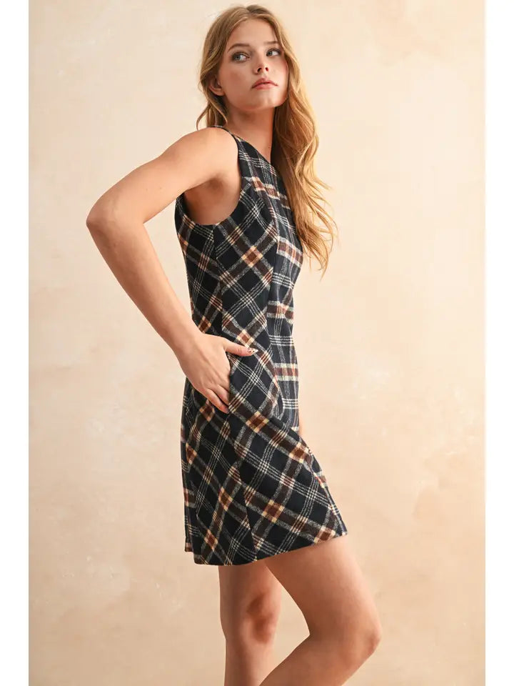 Woman wearing a plaid dress against a beige background