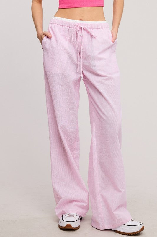 Pink sweatpants worn by a person on a plain background