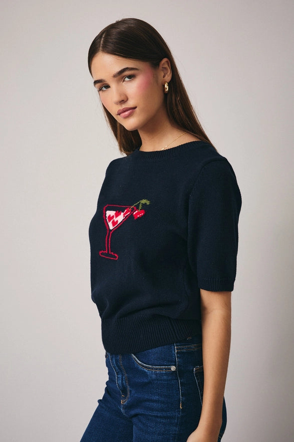 Woman wearing a navy sweater with a red and white design on a plain background