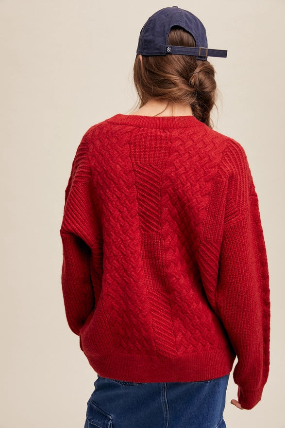 Woman standing against a plain background wearing a Red pull over sweater