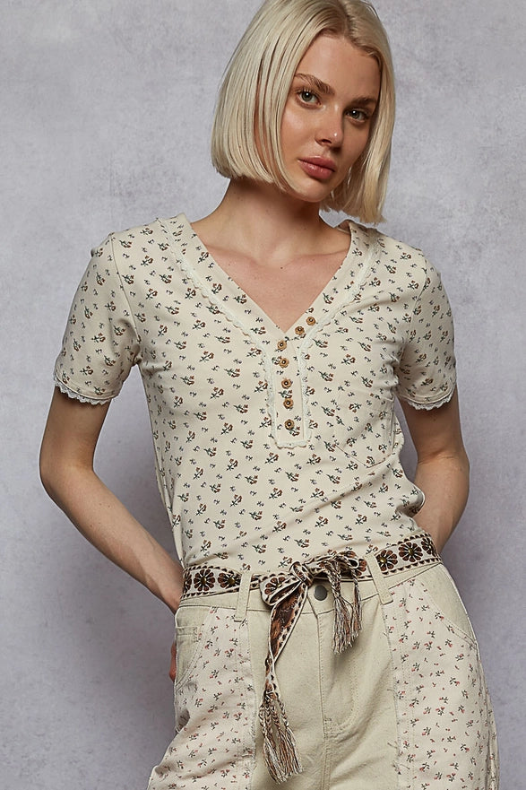 Woman wearing a floral blouse and pants against a gray background